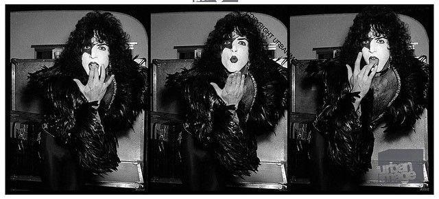 a black and white photo of a woman in a fur coat blowing a kiss .