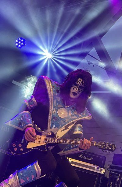 a man in a kiss costume is playing a guitar on a stage .