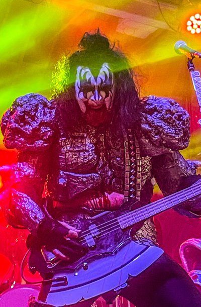 a man in a monster costume is playing a bass guitar on stage .