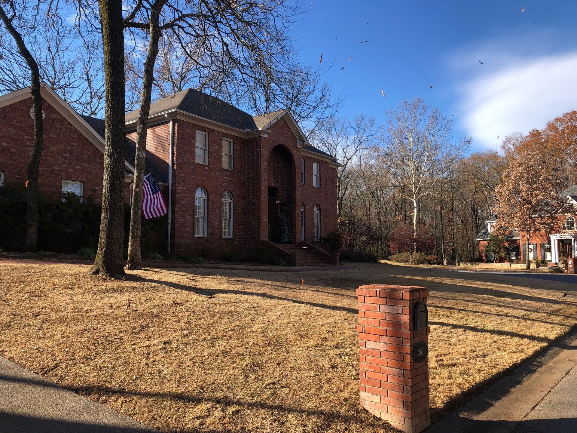 a large brick house with an american flag in front of it .