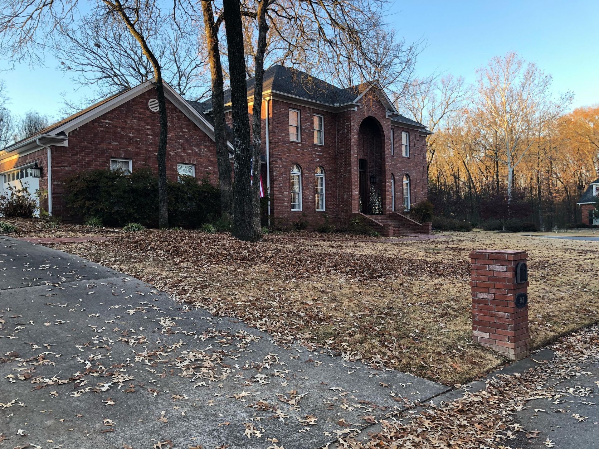 a large brick house with a lot of leaves on the ground in front of it .