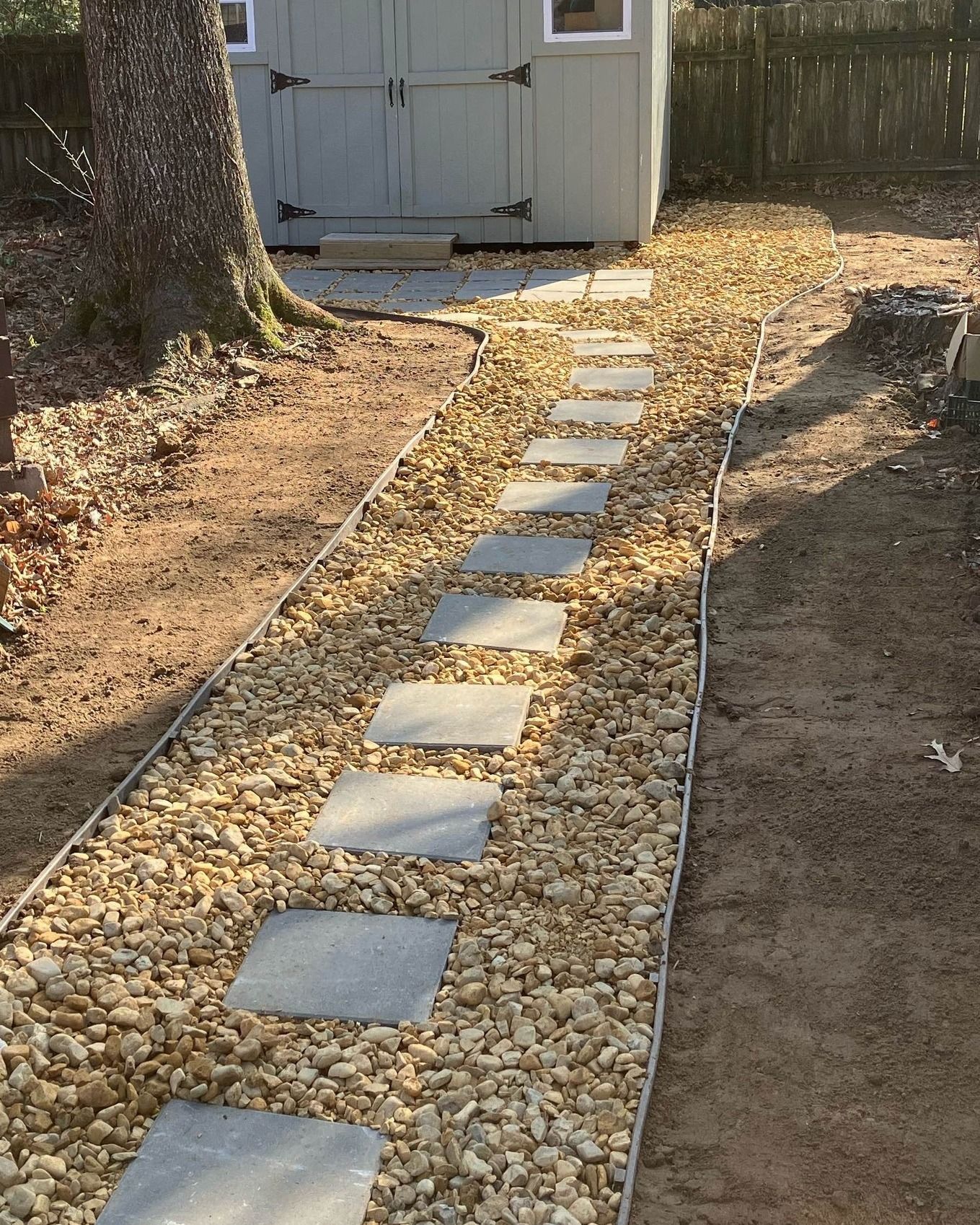 a stone walkway with a shed in the background