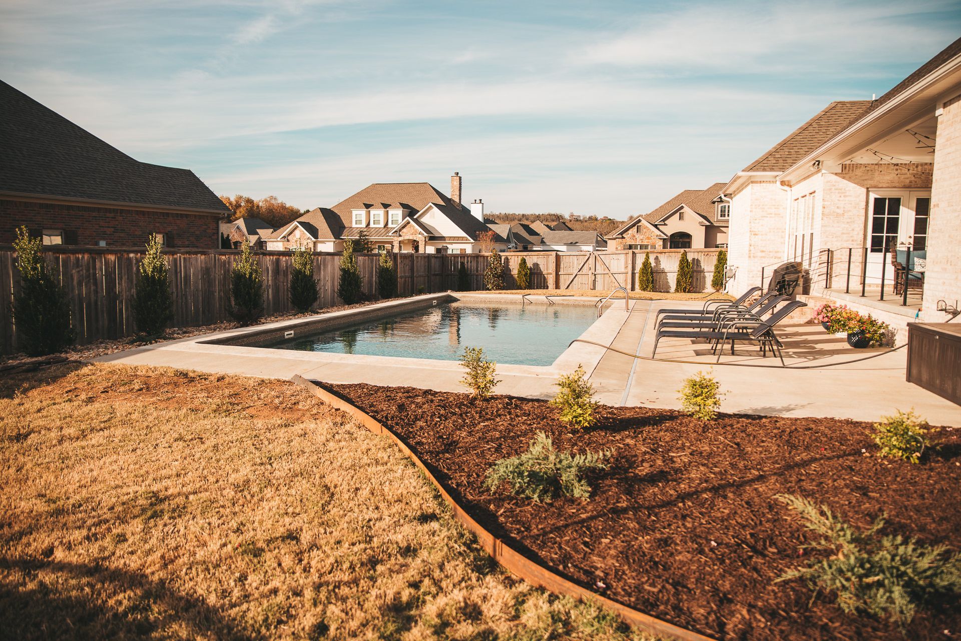 there is a large swimming pool in the backyard of a house .