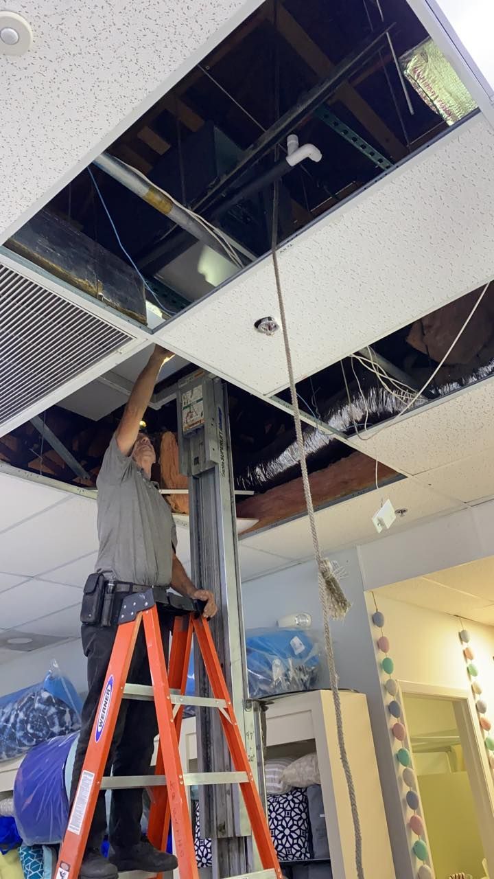 A man is standing on a ladder working on a ceiling.