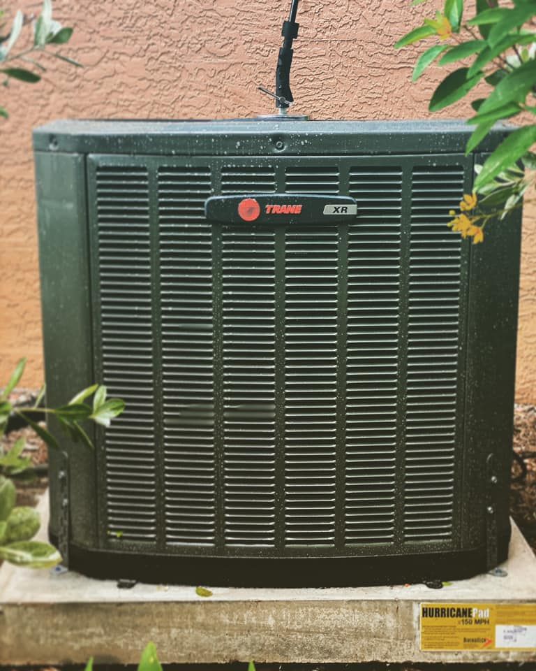 A black air conditioner is sitting on the side of a building.