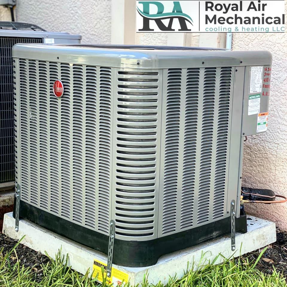 A royal air mechanical air conditioner is sitting on a concrete platform in the grass.