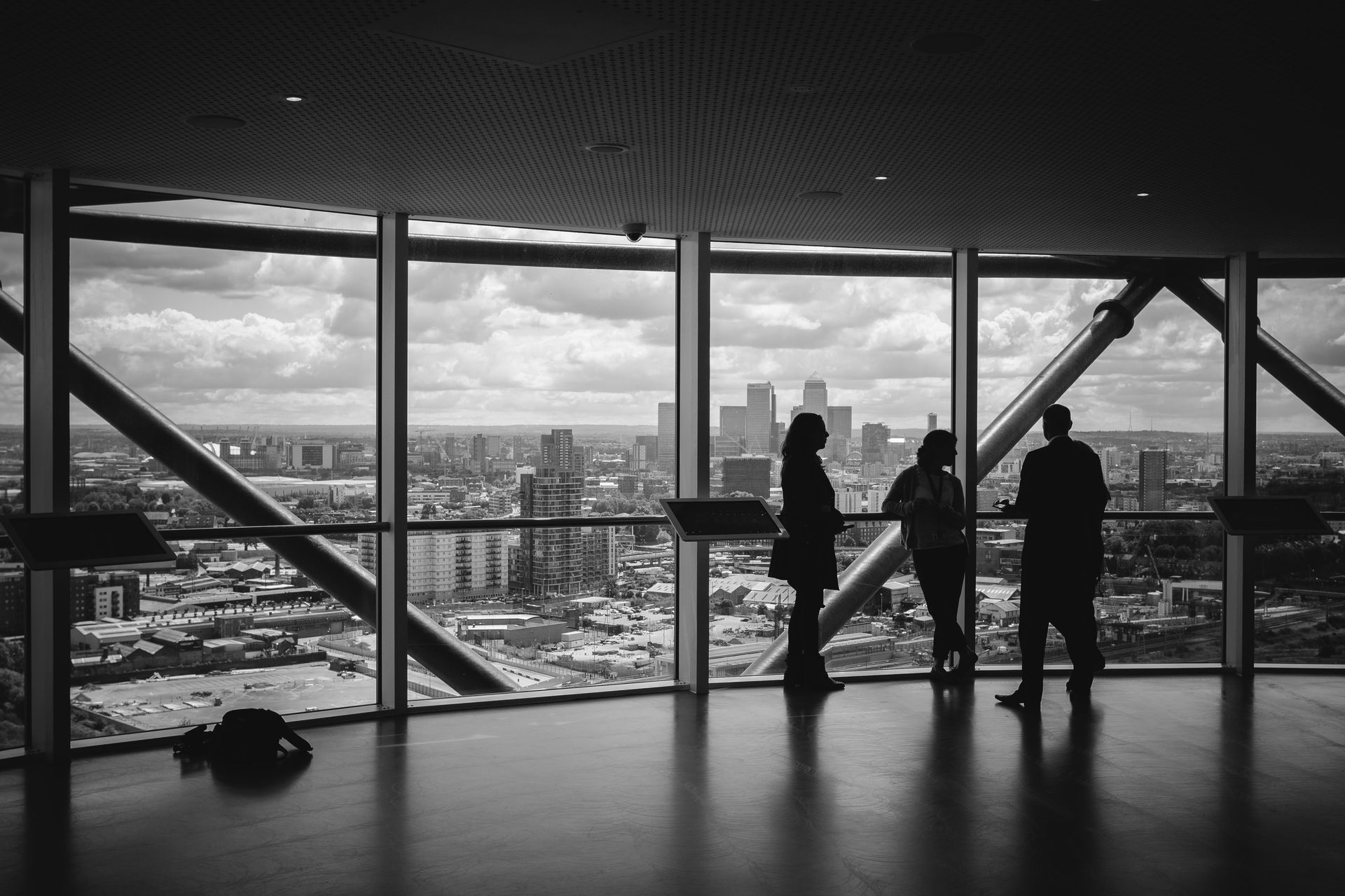 A group of people are standing in front of a large window overlooking a city.