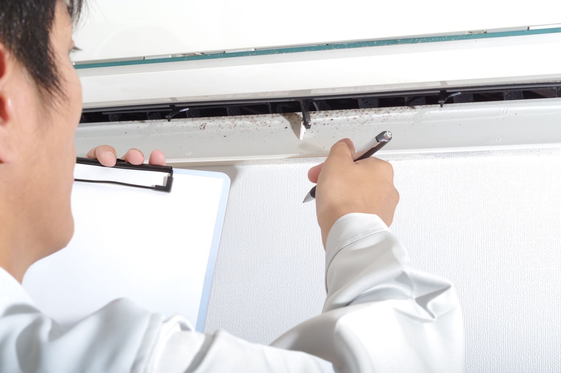 Person inspecting a ceiling crack with a pen and clipboard.