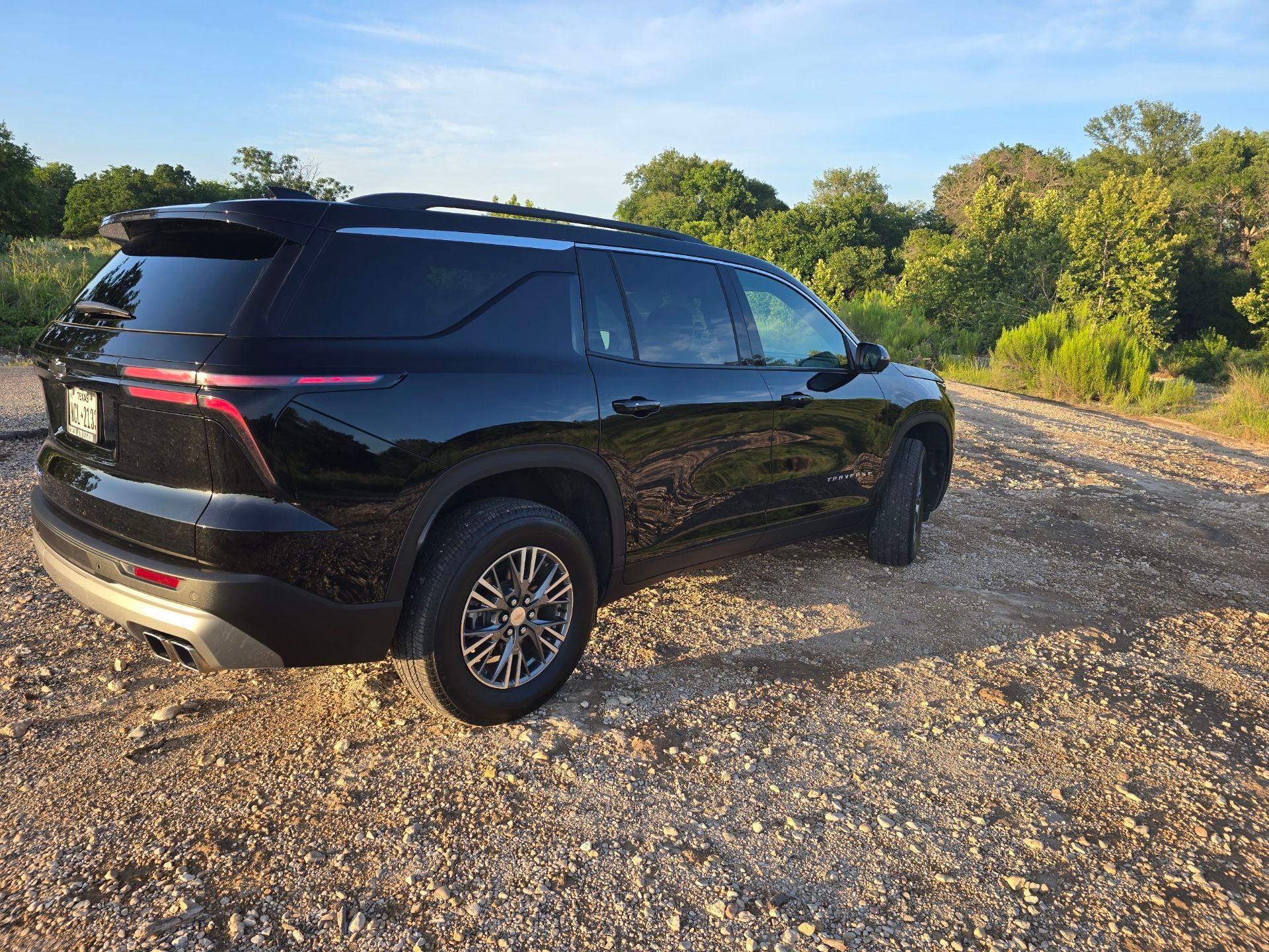 A black 2025 Chevy Traverse is parked on a gravel road.