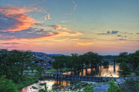 A sunset over a river with a bridge in the background in Kerrville TX