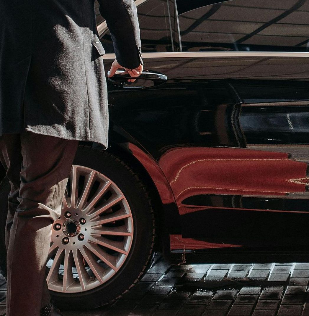 A man is opening the door of a red car