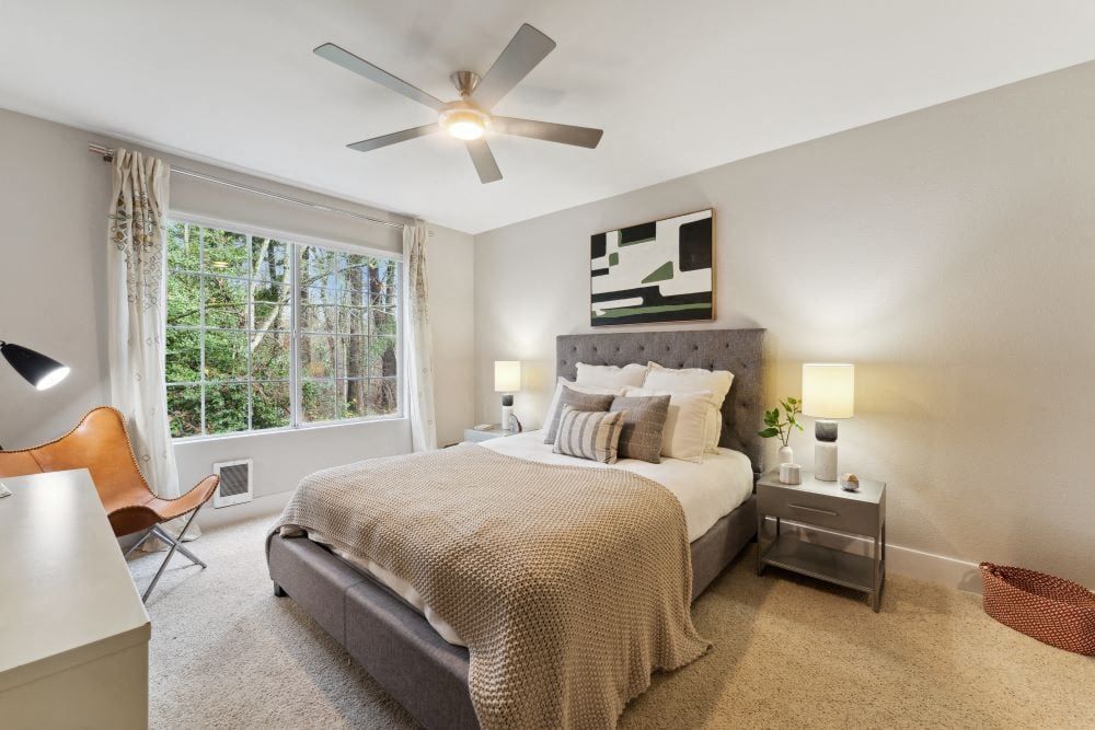 Bright bedroom with a queen bed, tufted headboard, two nightstands, and a large window at Sofi at Murrayhill, offers apartments near Washington Square Mall.