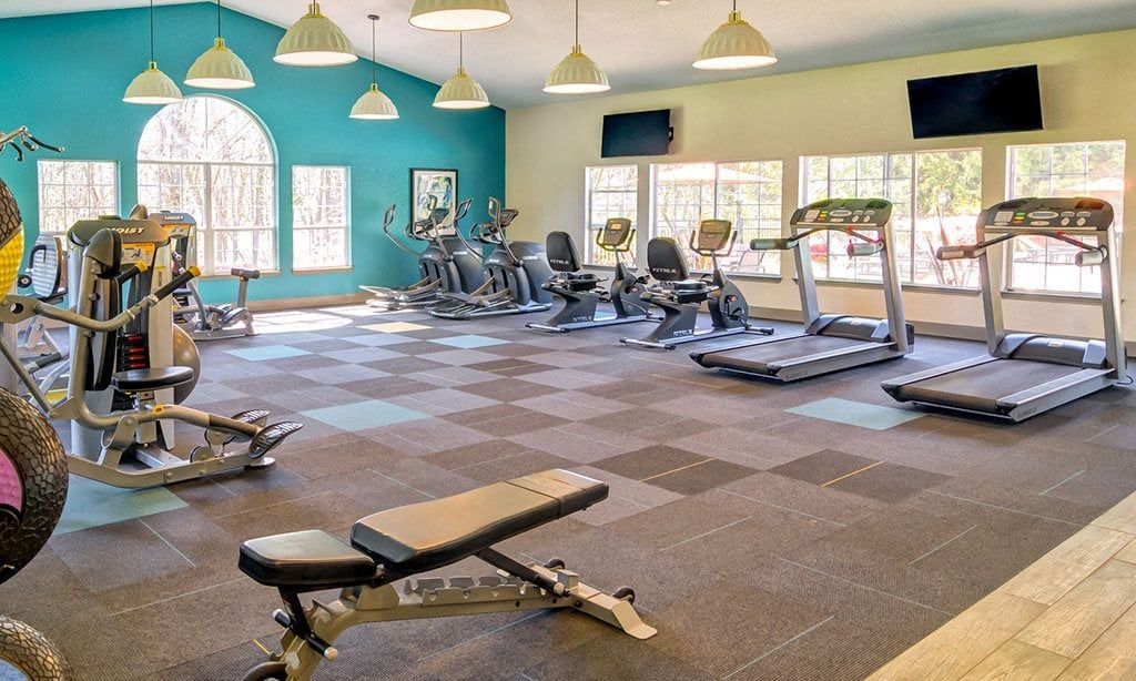 Fitness center with treadmills, ellipticals, stationary bikes, and a weight bench at Sofi at Murrayhill, offers apartments in Beaverton, OR.