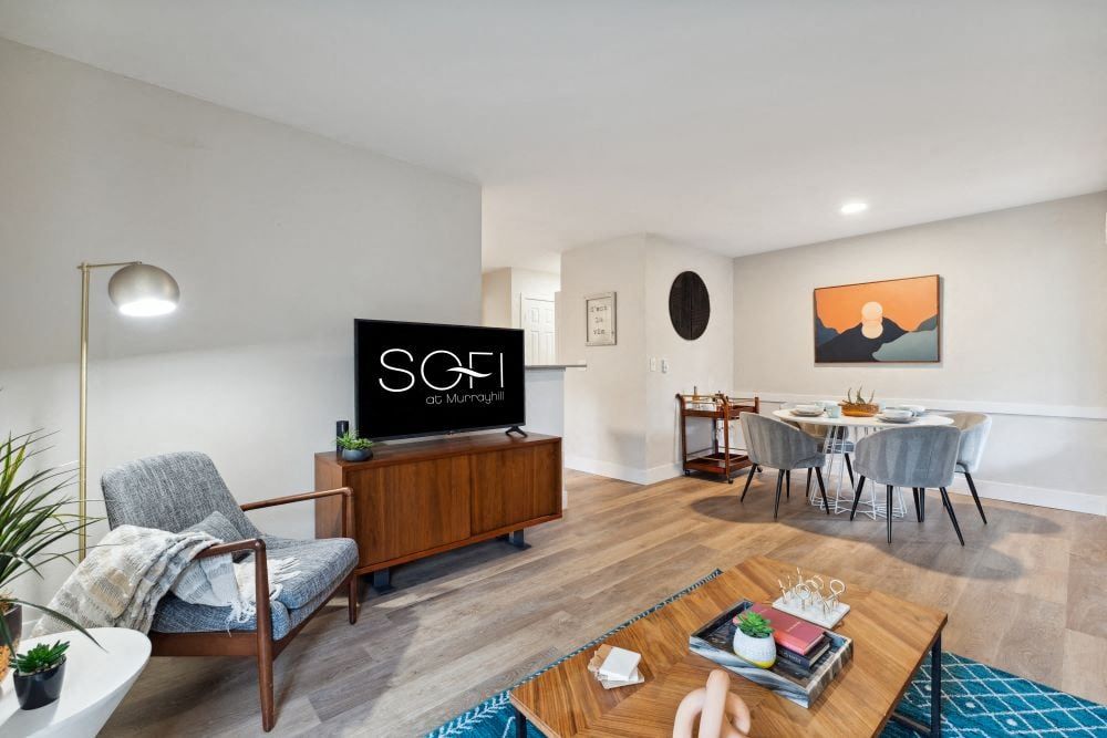 Living room and dining area in an apartment with a TV, seating, and a round dining table at Sofi at Murrayhill, offers apartments near Murrayhill Marketplace.