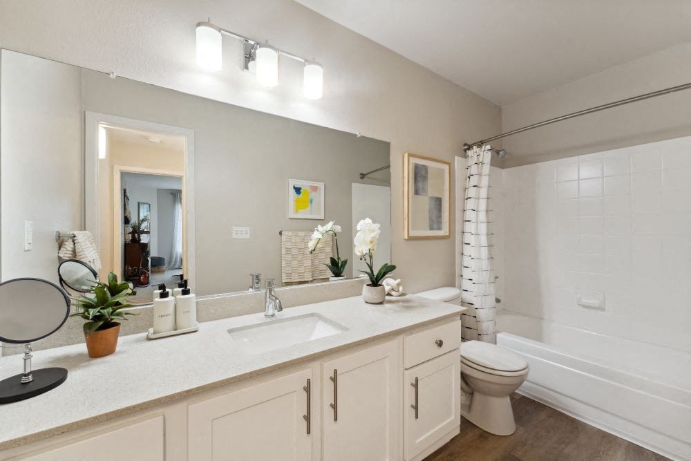 Bathroom with white vanity, quartz counter, large mirror, and tub/shower combo at Sofi at Murrayhill, offers apartments in Beaverton, OR.