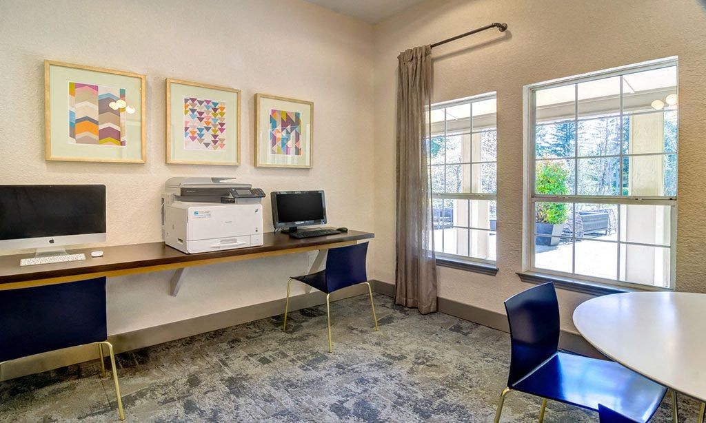 Shared community computer area with two desks, a printer, and a large window at Sofi at Murrayhill, offers apartments in Beaverton, OR.