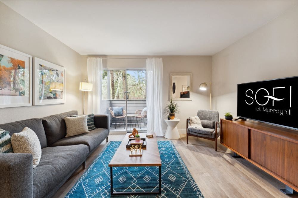 Bright living room in an apartment with a gray sofa, coffee table, and balcony doors at Sofi at Murrayhill, offers apartments near Murrayhill Marketplace.