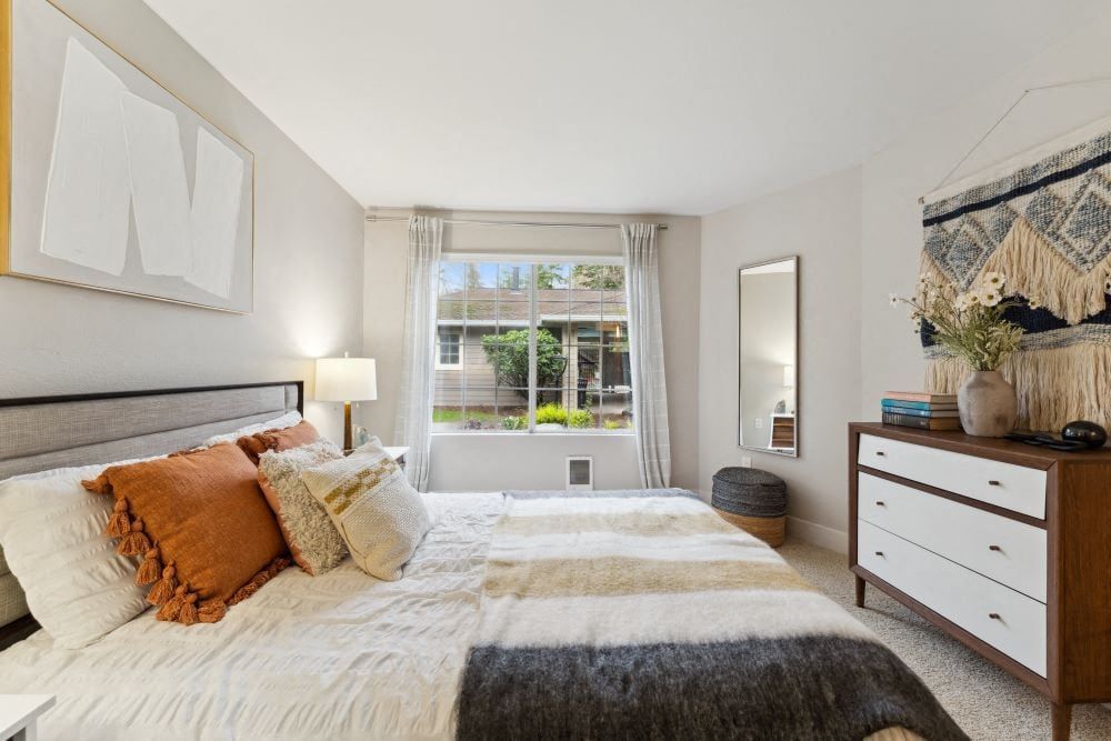 Bedroom with a bed, nightstand, dresser, and wall art, near a window with curtains.