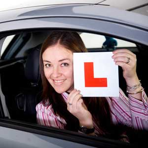 Smiling female learner driver holding up Learner sign