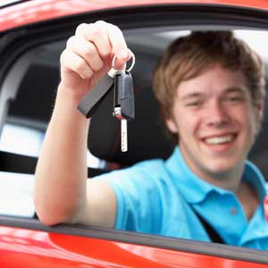 Young male driver  holding car keys, celebrating passing his test