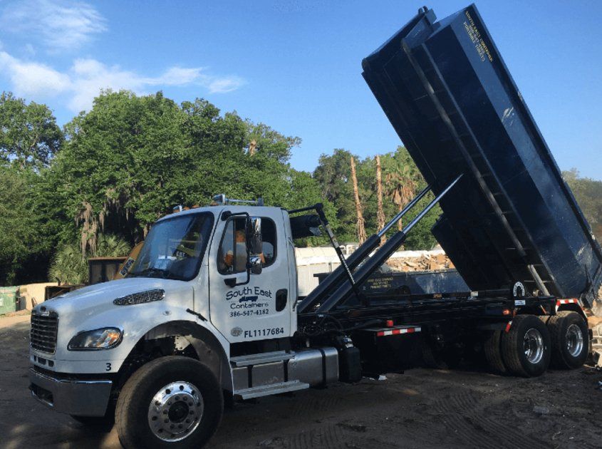 A dump truck is parked in a parking lot with the dumpster upside down.