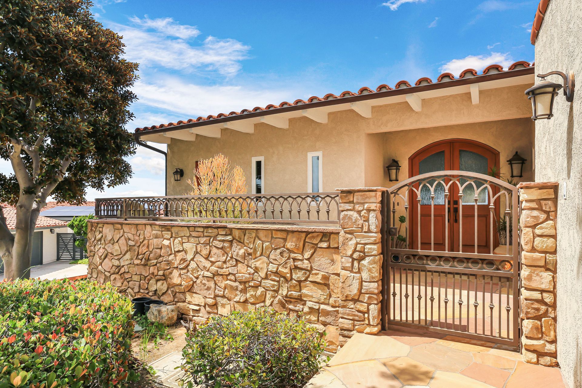 A house with a stone wall and a gate in front of it.