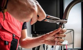 Repairman Using Adjustable Pliers to Fix Kitchen Faucet — Canberra , ACT — Discount Plumbing Heating & Cooling