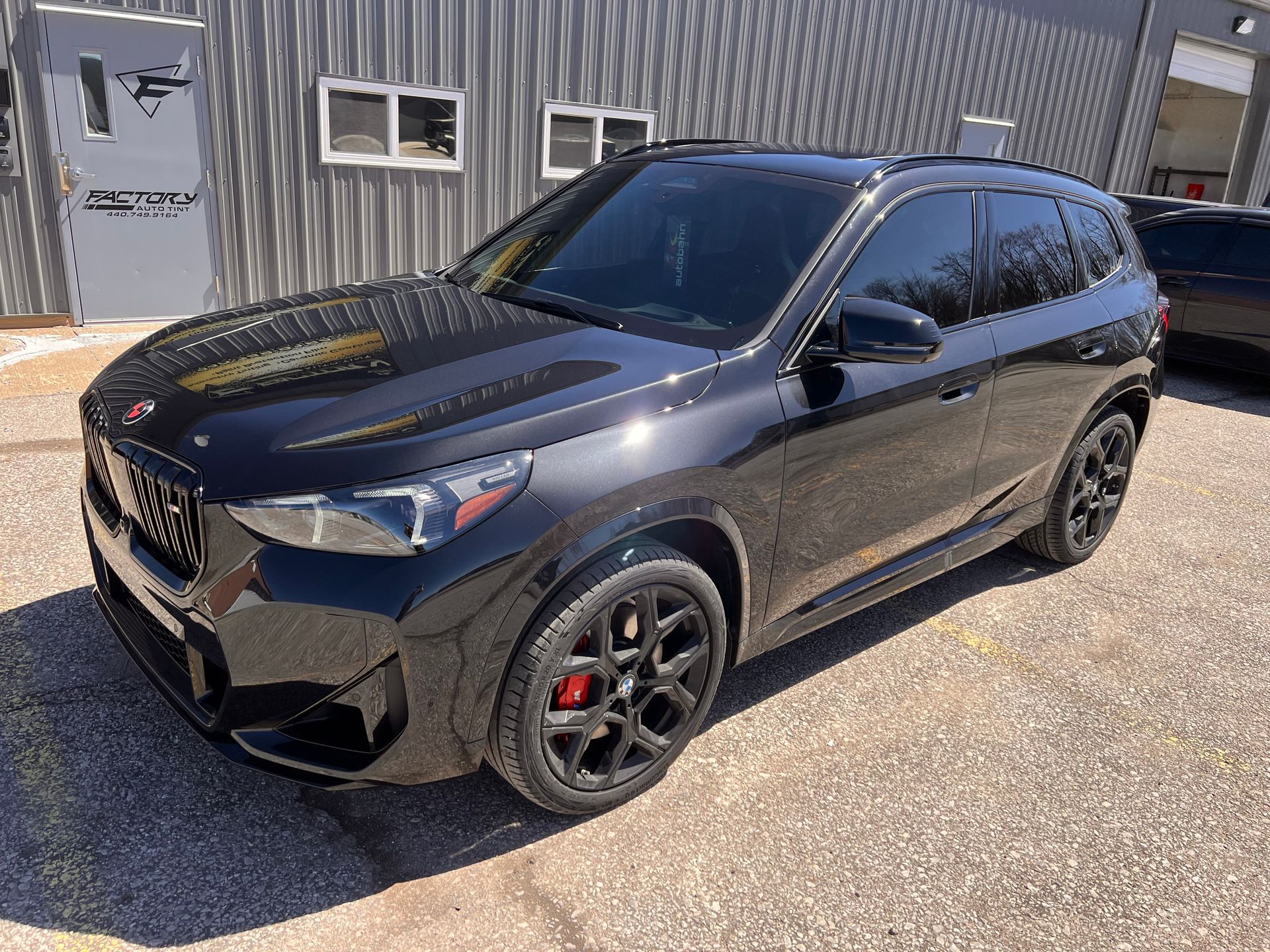 A black car is parked in front of a building.