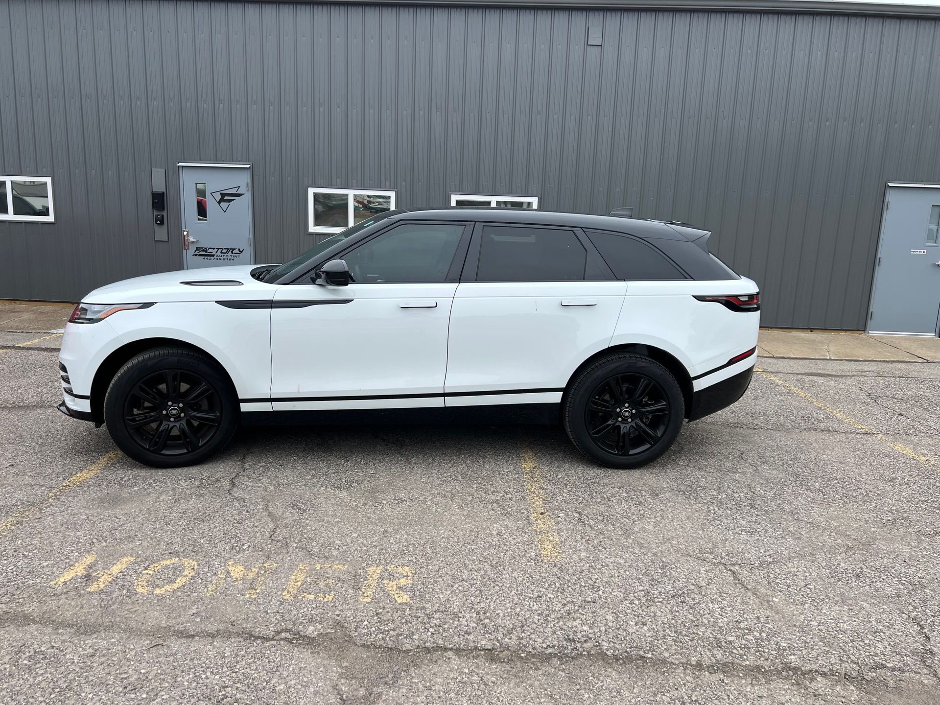 A white range rover velar is parked in front of a building.