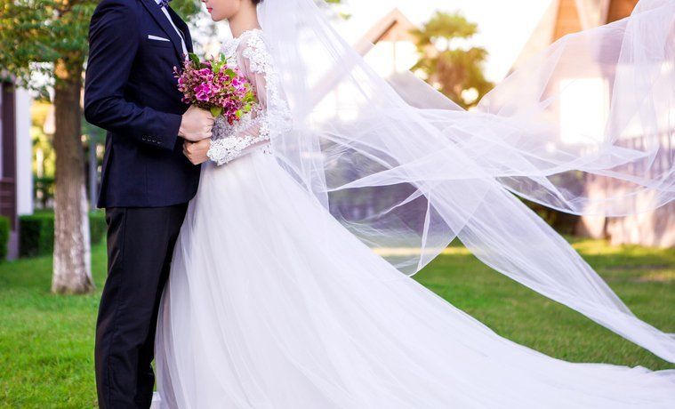 a bride and groom are posing for a picture with their veil blowing in the wind .