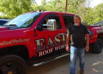 a man standing in front of a red truck that says east roof work
