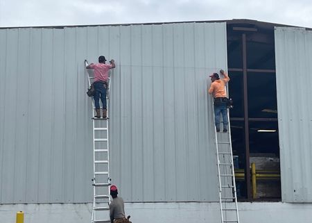 two men are climbing ladders on the side of a building .