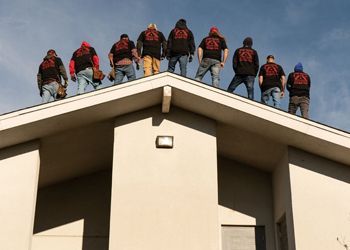 a group of men are standing on the roof of a building .