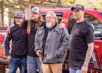 a group of men are posing for a picture in front of a red truck .