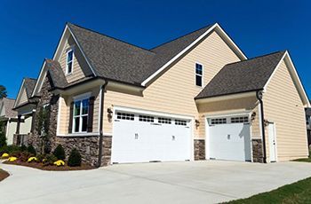 A large house with two garage doors and a blue sky in the background