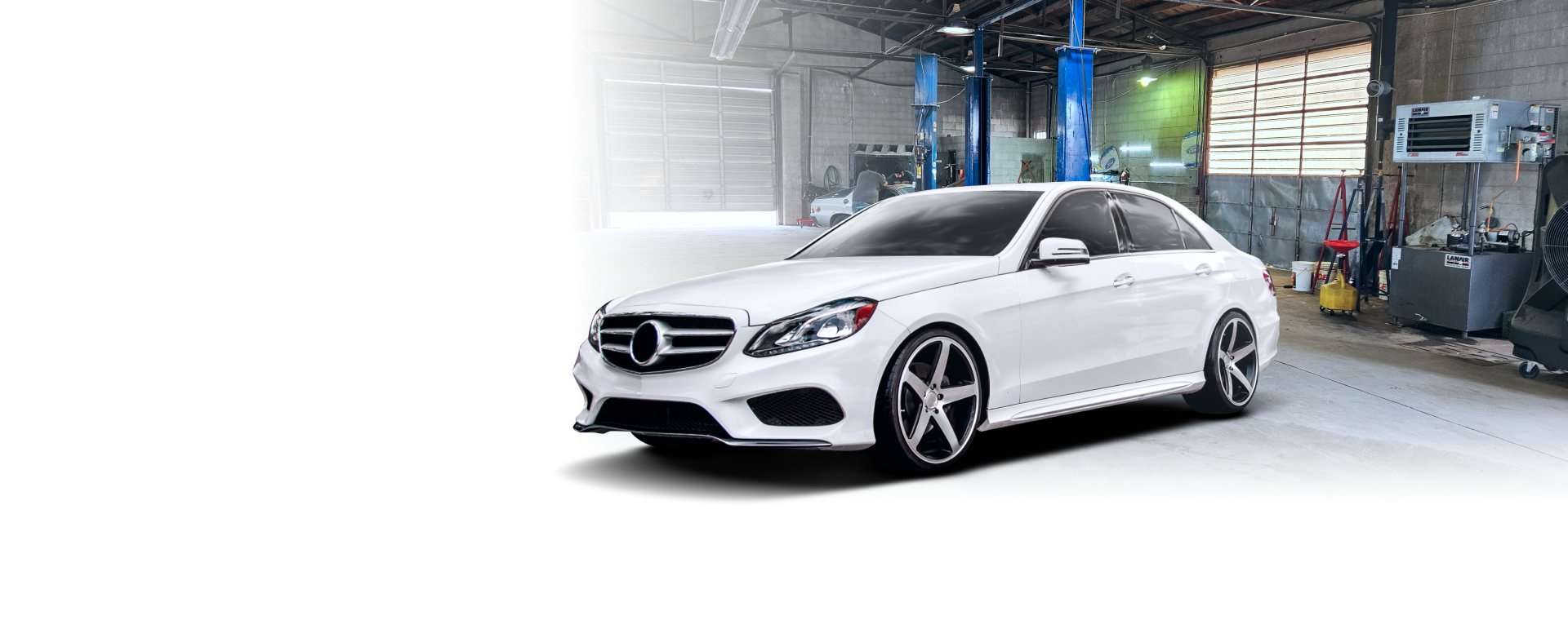 A white mercedes benz is parked in a garage.