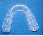 A clear mouth guard is sitting on top of a blue surface.