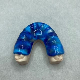 A blue mouth guard is sitting on a white surface