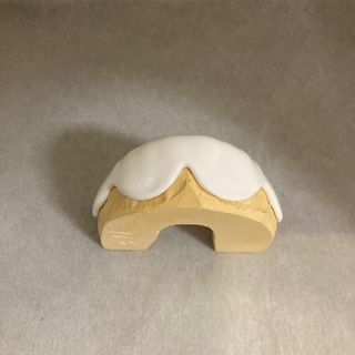 A small wooden object with a white frosting on top is sitting on a table.