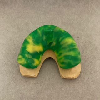 A green and yellow cookie is sitting on a table.