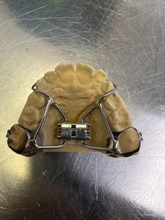 A dental model with braces on it is sitting on a stainless steel table.