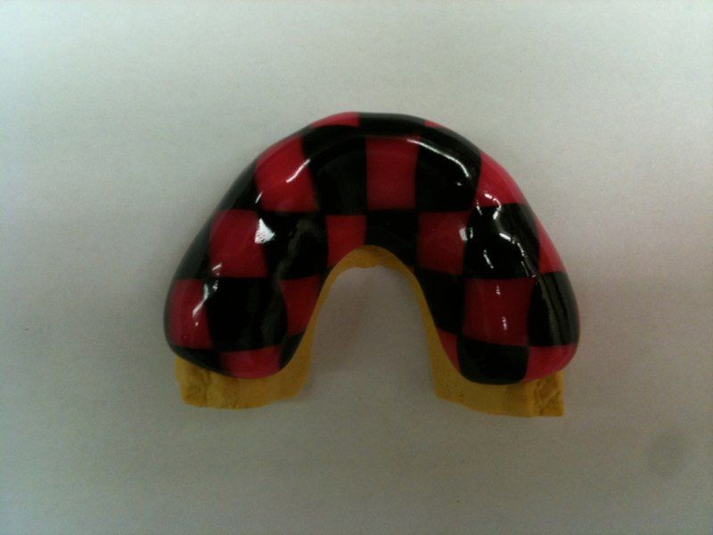 A red and black checkered mouth guard on a white surface