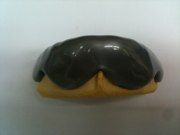 A close up of a donut with chocolate frosting on a white surface.