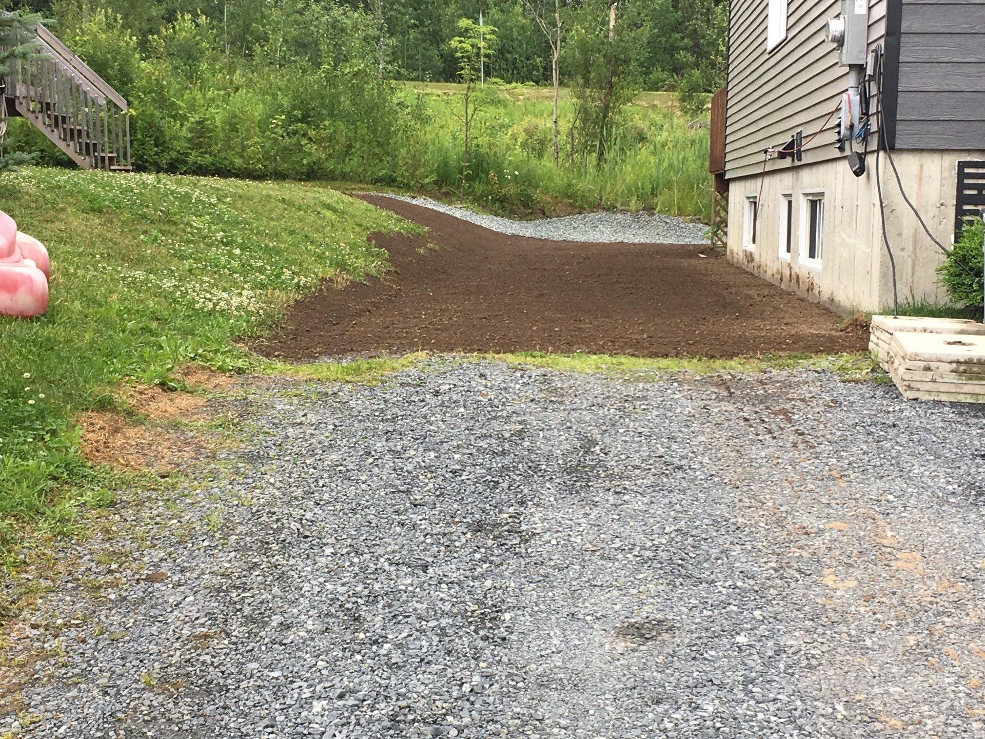 Une allée de gravier menant à une maison avec un flamant rose dans l'herbe.