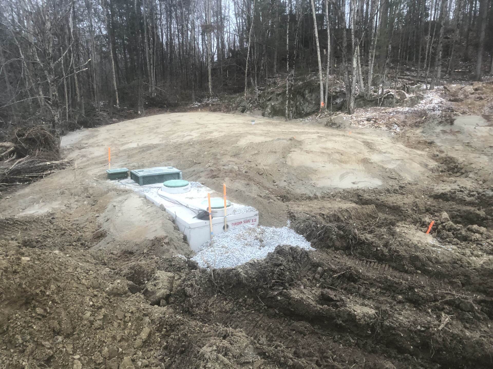 Un gros tas de terre se trouve au sommet d'un champ de terre au milieu d'une forêt.