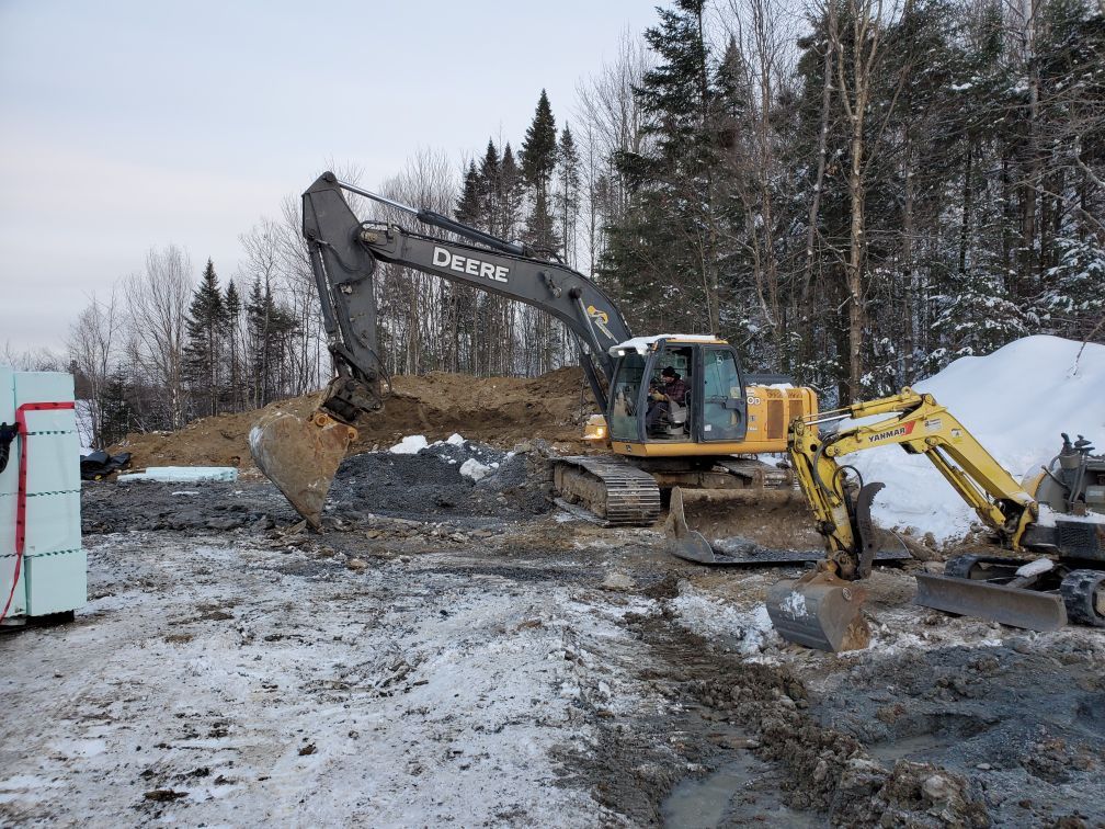 Une grande excavatrice creuse un trou dans la neige.
