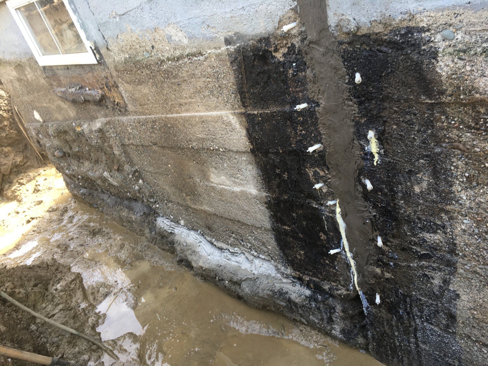 Un mur en béton avec un trou dedans et de l'eau qui en sort.