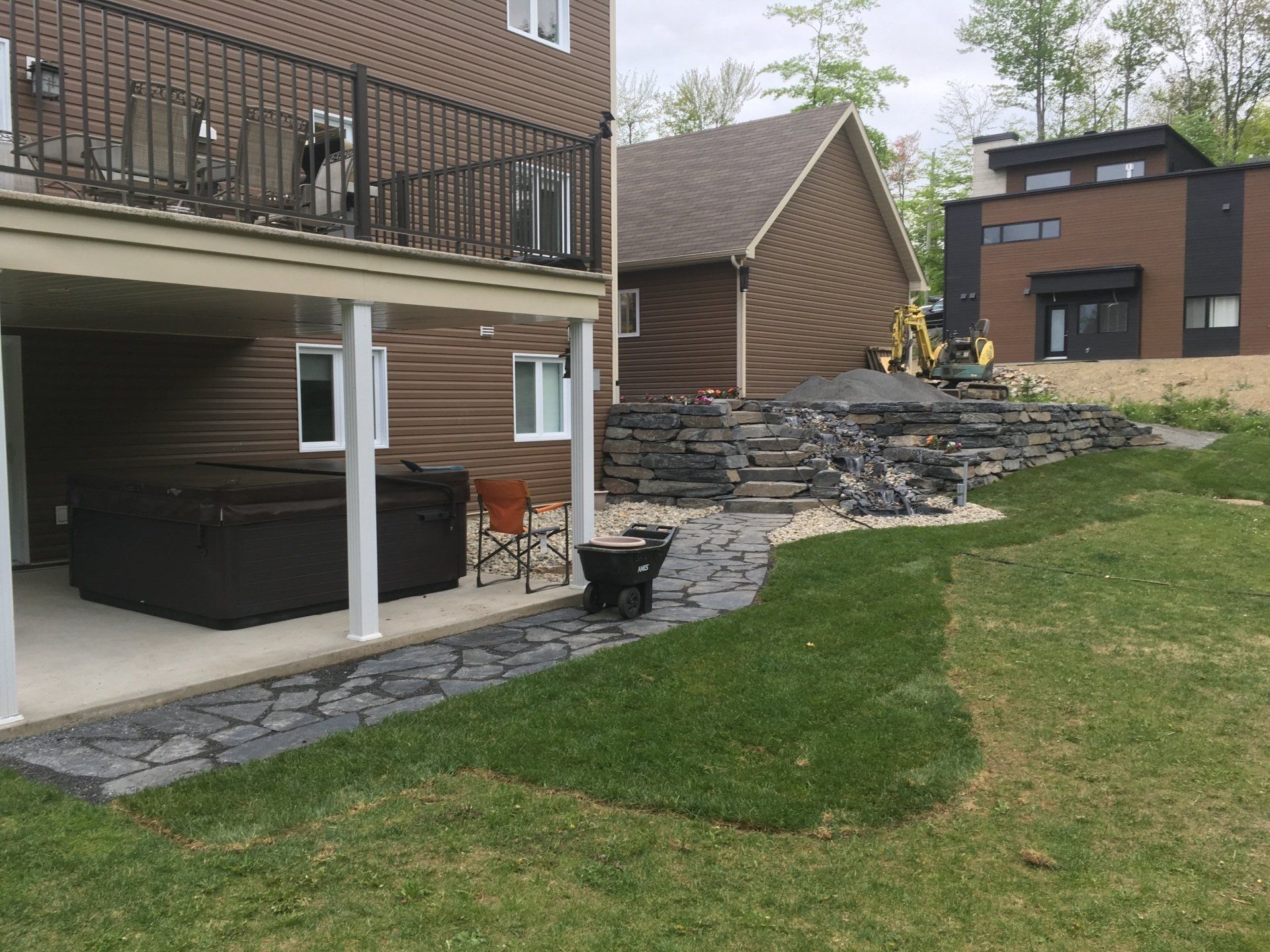 Une maison avec un jacuzzi sous une terrasse dans l'arrière-cour.