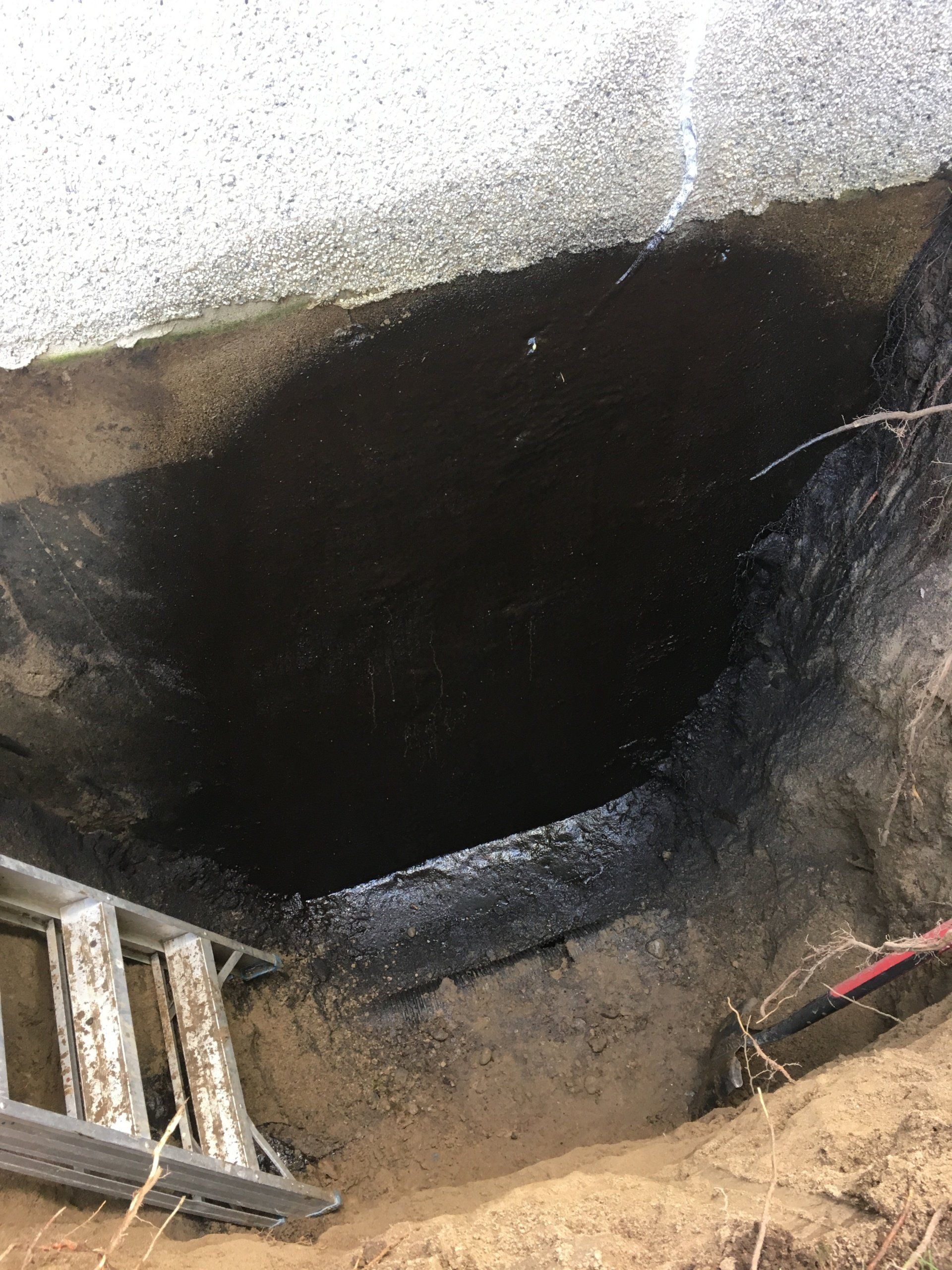 Une échelle est posée dans la terre à côté d'un trou dans le sol.