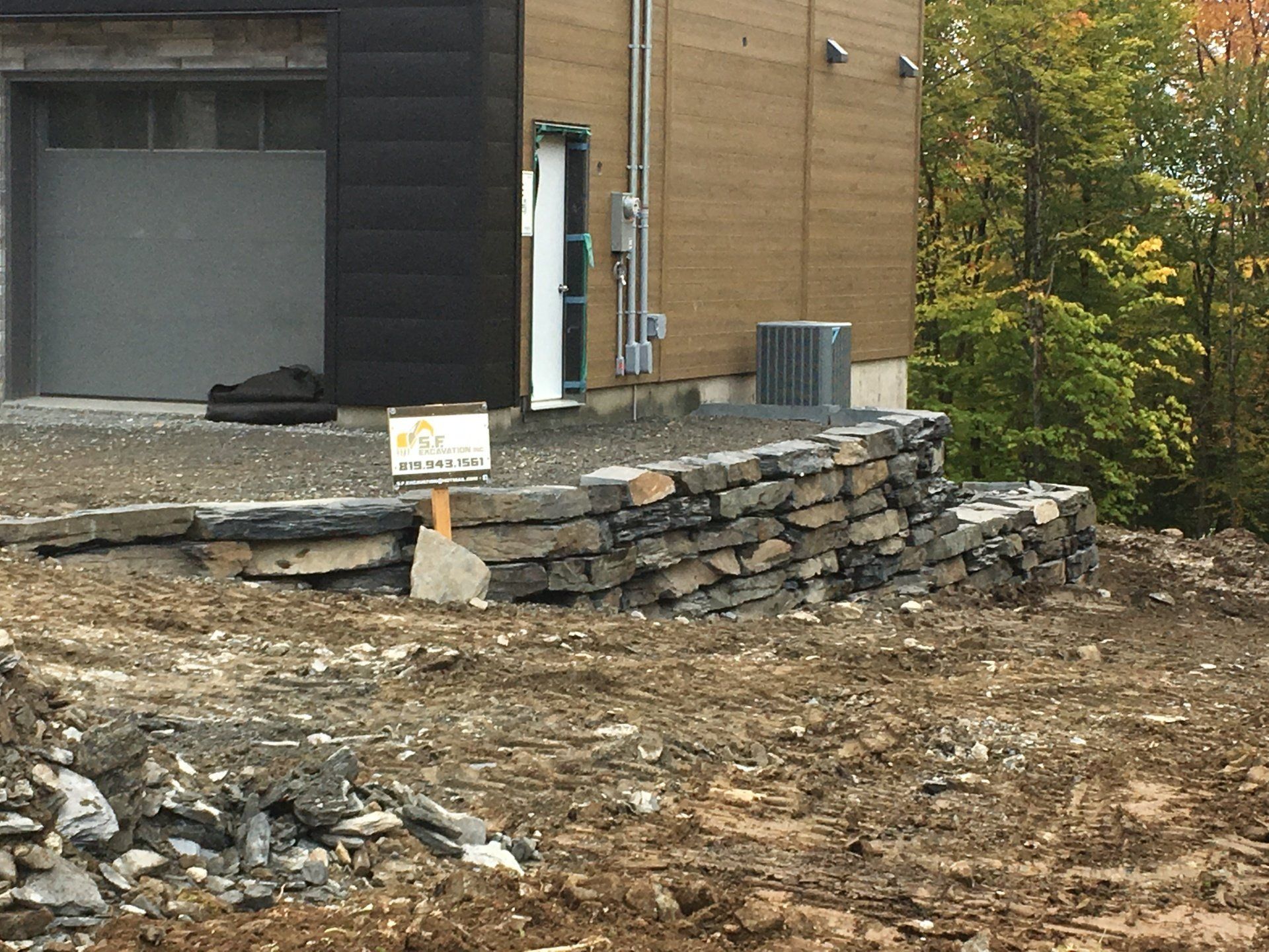 Un mur de pierre est en train d'être construit devant une maison.